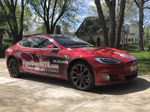 Red Tesla with business graphics on the doors