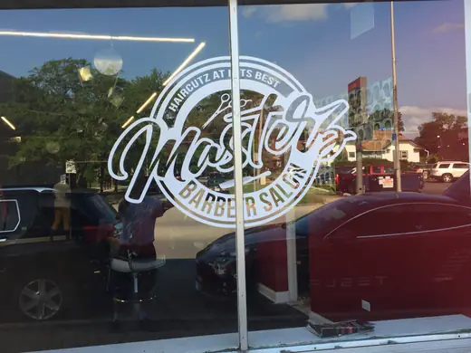 Shop window with a large white logo graphic, street reflections visible